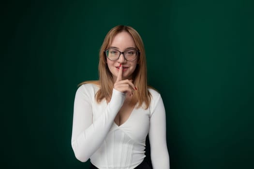 A woman with glasses standing and posing for a photo, smiling at the camera. She looks confident and stylish in her pose, with a neutral background.