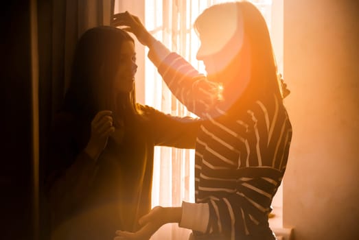 Two female friends of different ethnicity are embracing in the sun and happy to meet each other. Girls celebrate the holidays and hug tightly and warm, feel an emotional connection and love.