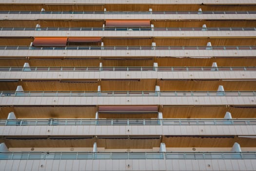 Close-up of a symmetrical residential building facade with balconies and orange awnings. Sant Antoni beach, Cullera, Spain