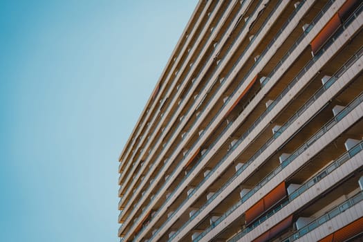 An angled view of a residential building s facade with multiple balconies and a clear sky above. Sant Antoni beach, Cullera, Spain