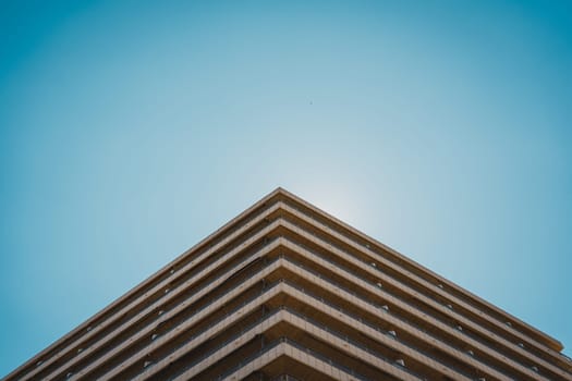 Unique perspective of a building s corner facade with balconies, set against a clear sky. Sant Antoni beach, Cullera, Spain