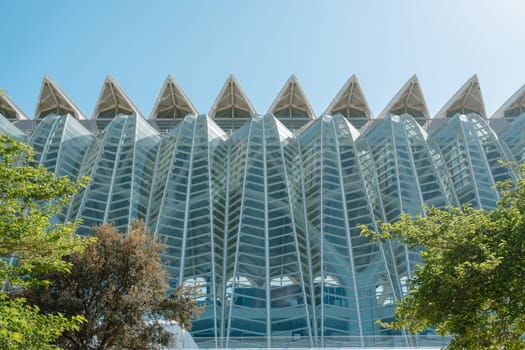 Contemporary architectural marvel striking glass facade. The geometric design features sharp angles and intricate patterns, set against a clear sky, highlighting innovative urban construction.