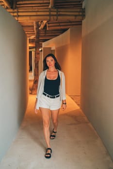 A woman walking in a passageway with bamboo ceilings. The architectural setting is minimalistic and serene, emphasizing clean lines and natural materials. The woman is focused, with a calm demeanor.