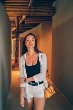 A woman walks through a bamboo-ceiling corridor, smiling. The natural materials and soft lighting create a warm, inviting ambiance, blending traditional design with modern aesthetics.