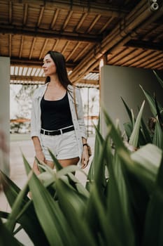 A woman walks through a bamboo-covered pathway. The setting features lush plants and a serene atmosphere, emphasizing a connection with nature and a relaxed, contemplative mood.