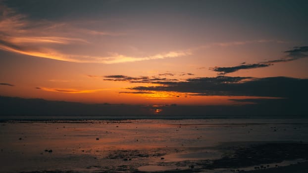 A tranquil beach scene at sunset with a vibrant sky reflecting on calm waters. The serene setting captures the peaceful transition of day to night, emphasizing nature s beauty and tranquility.