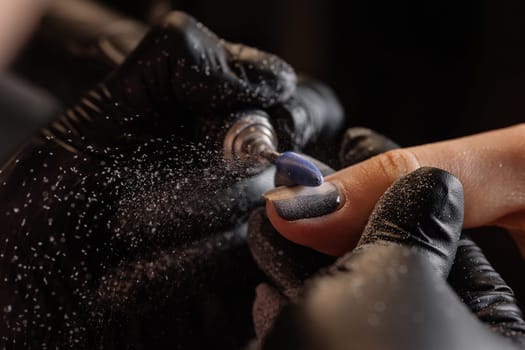 A manicurist gives a hardware manicure to a client using special tools. nail salon, self care concept