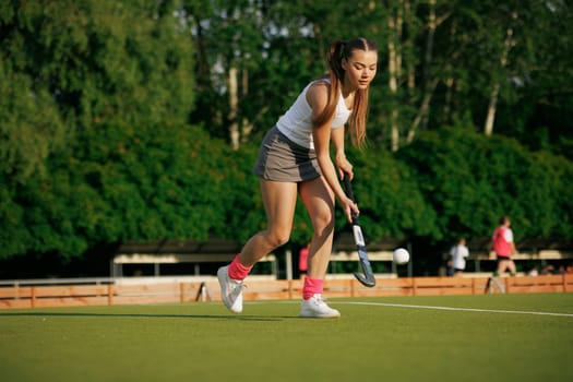 girl hockey player plays field hockey on a sunny day, female hockey player hits the ball with a stick, field hockey concept
