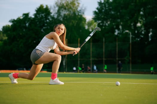 girl hockey player plays field hockey on a sunny day, female hockey player hits the ball with a stick, field hockey concept