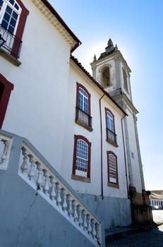 A traditional colonial church with red-framed windows stands under a clear blue sky.