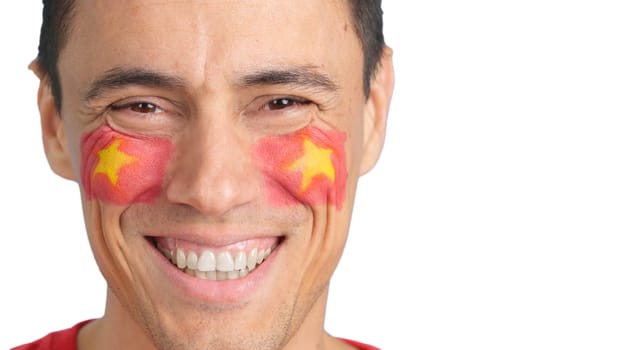 Close up of a man with a vietnamese flag painted on the face smiling at camera