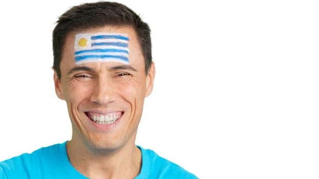 Close up of a man with a uruguayan flag painted on the face smiling at camera