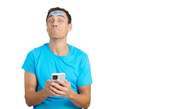 Uruguayan supporter with the flag of Uruguay painted on his face, looking at his mobile phone smiling