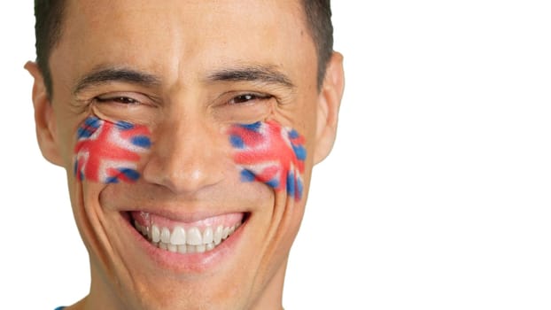 Cose up of a man with a british flag painted on the face smiling at camera