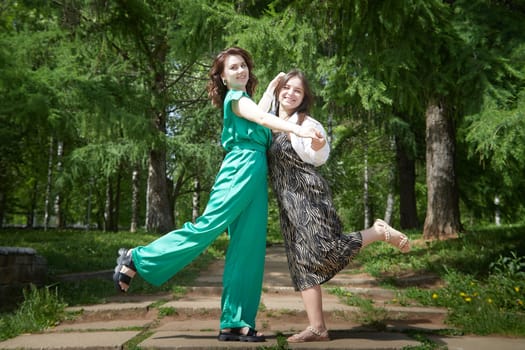 Portrait of happy girls in the park in summer. Female friends together. Young women pose in sunny park during summer, enjoying time outdoors