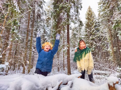 Two cute happy little cheerful children walking and having fun in winter snow forest. Photo shoot in stylized clothes of the USSR. Fur Hat with earflaps