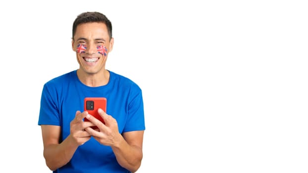 British supporter with the flag of United Kingdom painted on his face, looking at his mobile phone smiling