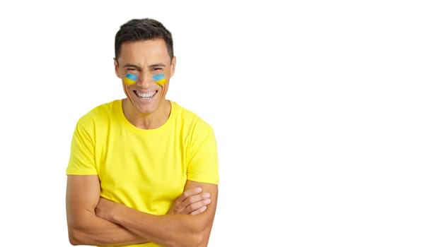 Man standing with ukrainian flag painted on face smiling with arms crossed