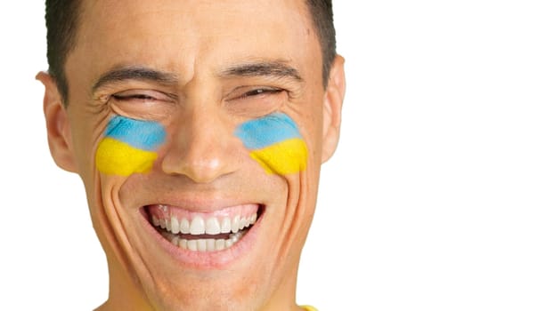 Close-up of a caucasian man with a ukrainian flag painted on the face smiling at camera