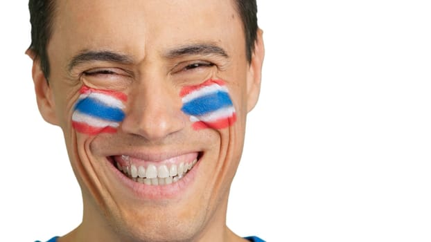 Close up of a man with a thai flag painted on the face smiling at camera