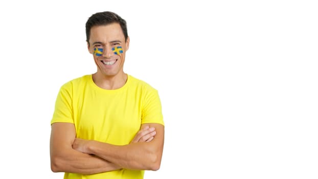 Man standing with swedish flag painted on face smiling with arms crossed