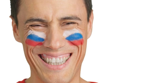 Close up of a man with a russian flag painted on the face smiling at camera