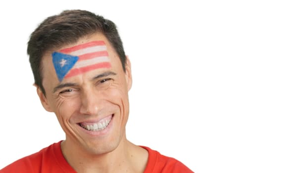 Close up of a man with a puerto rican flag painted on the face smiling at camera