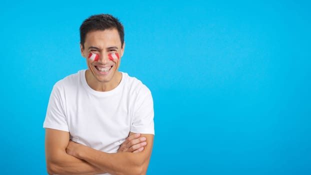 Man standing with peruvian flag painted on face smiling with arms crossed