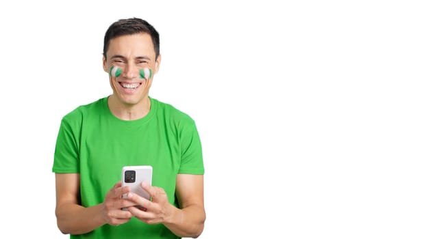 Nigeria supporter with the flag of Nigeria painted on his face, looking at his mobile phone smiling