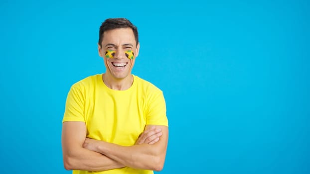 Man standing with jamaican flag painted on face smiling with arms crossed