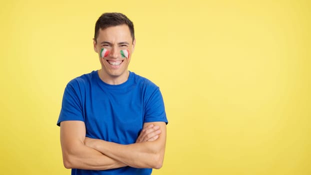Man standing with italian flag painted on face smiling with arms crossed