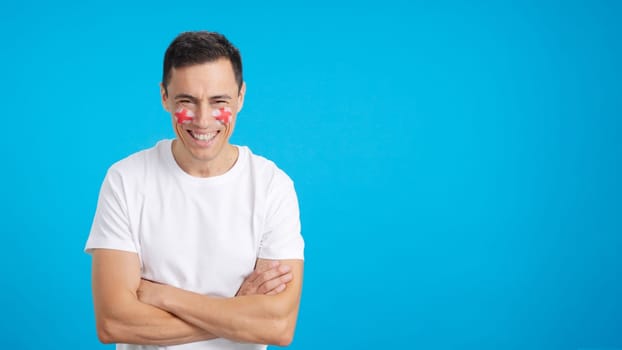 Man standing with english flag painted on face smiling with arms crossed