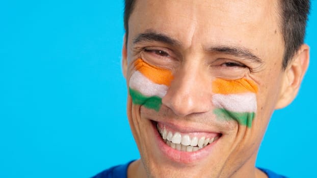 Close-up of a man with a indian flag painted on the face smiling at camera