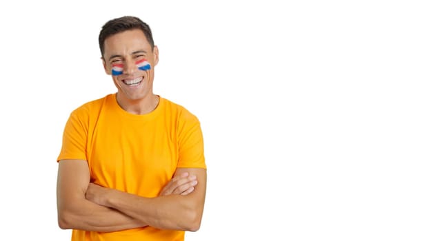 Man standing with dutch flag painted on face smiling with arms crossed