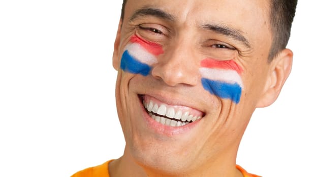 Close up of a man with a dutch flag painted on the face smiling at camera