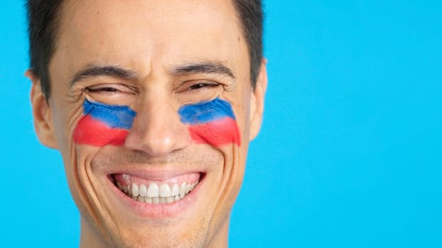 Close up of a man with a haitian flag painted on the face smiling at camera