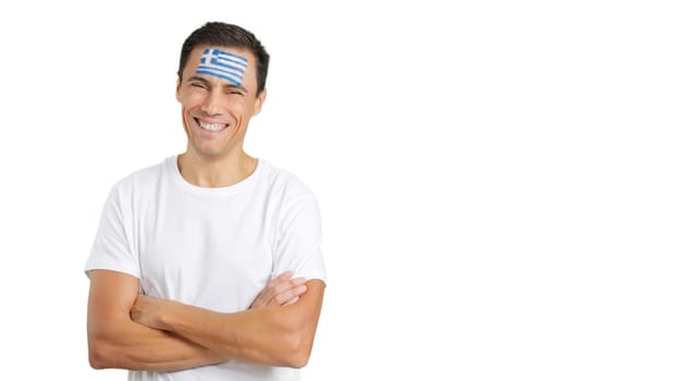 Man standing with greek flag painted on face smiling with arms crossed