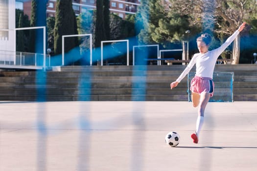 female football player kicking a soccer ball into the goal on an urban field, concept of sport and active lifestyle, copy space for text