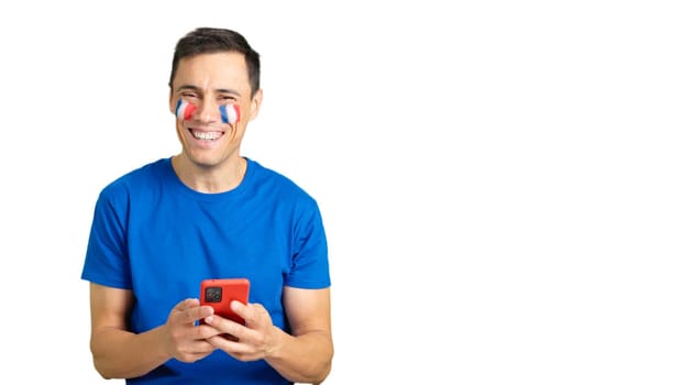 French man with the flag of France painted on his face, looking at his mobile phone smiling