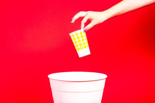 Closeup hand throwing empty paper disposable coffee cup in a recycling bin. Eco friendly concept.