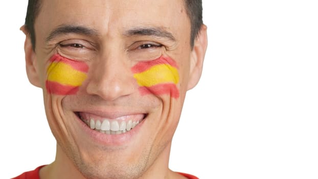Close-up of a caucasian man with a spanish flag painted on the face smiling at camera
