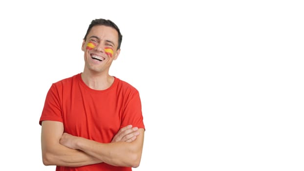 Man standing looking at camera with spanish flag painted on face smiling with arms crossed