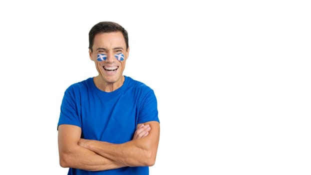 Man standing with scottish flag painted on face smiling with arms crossed