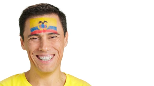 Close up of a man with a ecuadorian flag painted on the face smiling at camera