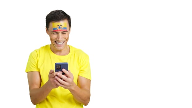 Ecuadorian supporter with the flag of Ecuador painted on his face, looking at his mobile phone smiling