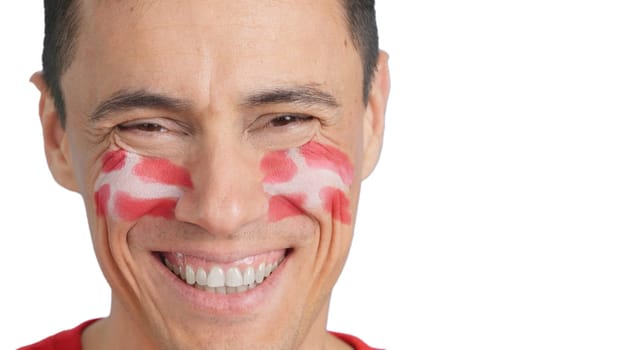 Close up of a man with a danish flag painted on the face smiling at camera