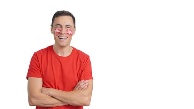 Man standing with danish flag painted on face smiling with arms crossed