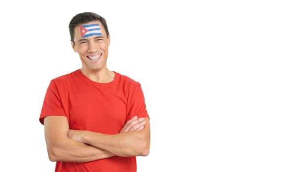 Man standing with cuban flag painted on face smiling with arms crossed