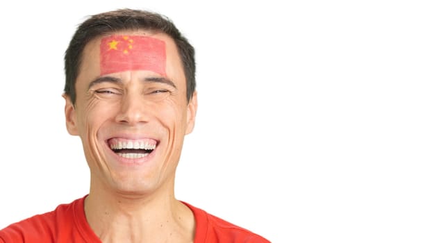 Close up of a caucasian man with a chinese flag painted on the face smiling at camera