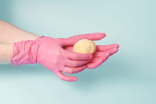 Close-up on female hands of a cook in rubber gloves holding raw mantu from dough with meat, concept of neat production of semi-finished food.